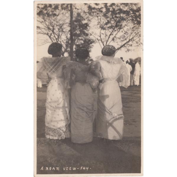 Front of a postcard showing the backs of three women in traditional dress.