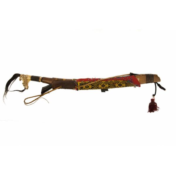 A large axe and a small knife a sheath with two holders. The axe has an ivory-coloured handle shaped like a dragon head with two tufts of black hair coming out of it. The knife has a dark wood handle. The smaller sheath is visible and is made from wood covered in red fabric and a strip of yellow and black beads. There is a burgundy tassel hanging off of the end from a piece of black string. 