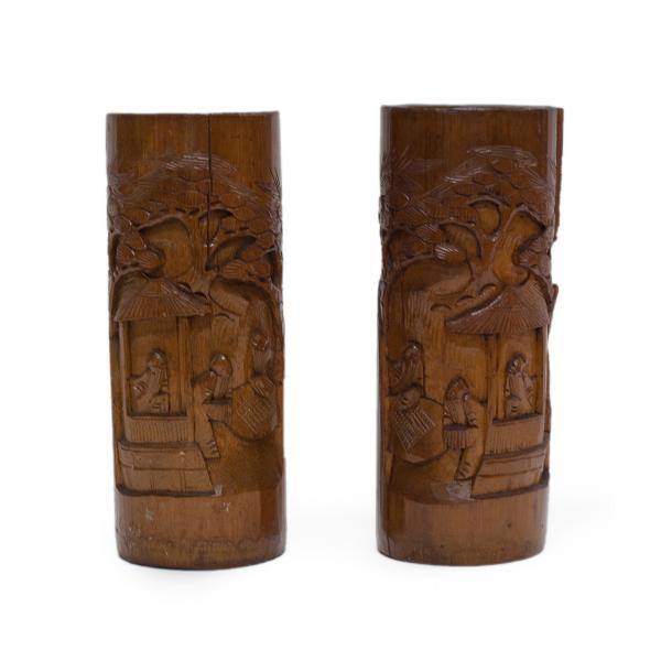 Two carved brown wooden vases. There are images carved into the vases of three bearded men standing near a roofed structure with a tree in the background. The relief images on the vases are mirror images of each other.