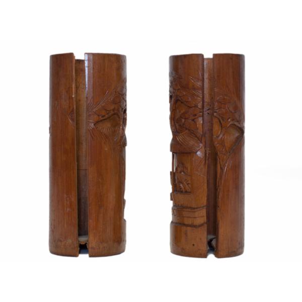 The back of two brown wooden vases. There is a section cut out of the centre of each. Part of a carved image of a roofed structure is visible. 