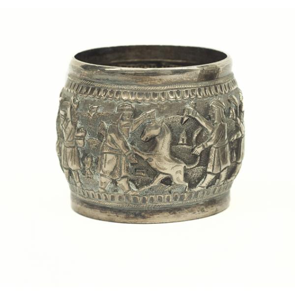 A silver napkin ring showing two figures stabbing a deer with daggers.