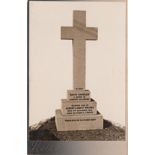 Grave marker for David Charles Holmes shaped like a cross on top of a three-stepped base. 