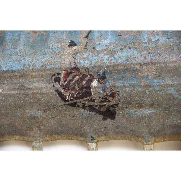 A painting on a sawfish snout of two men in a fishing boat. 