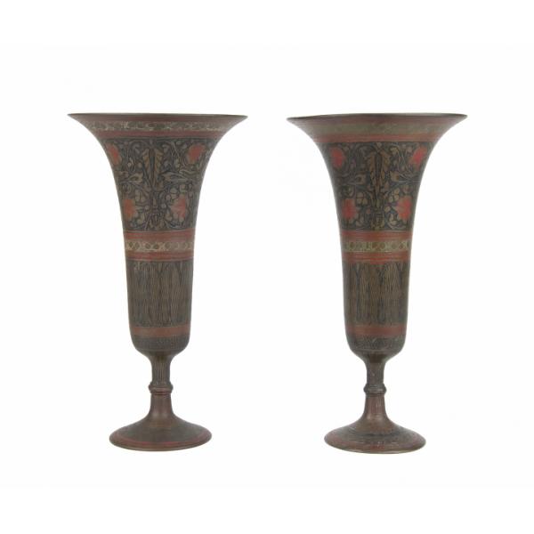 Deux vases en laiton à bord évasé et base en piédestal. Il y a un motif floral peint sur chacun des vases, en rouge, noir et jaune. 