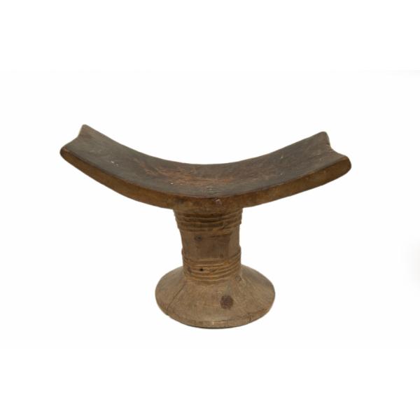 A wooden head rest. A curved piece sits on top of a base that widens at the bottom and has a series of ridges around it.