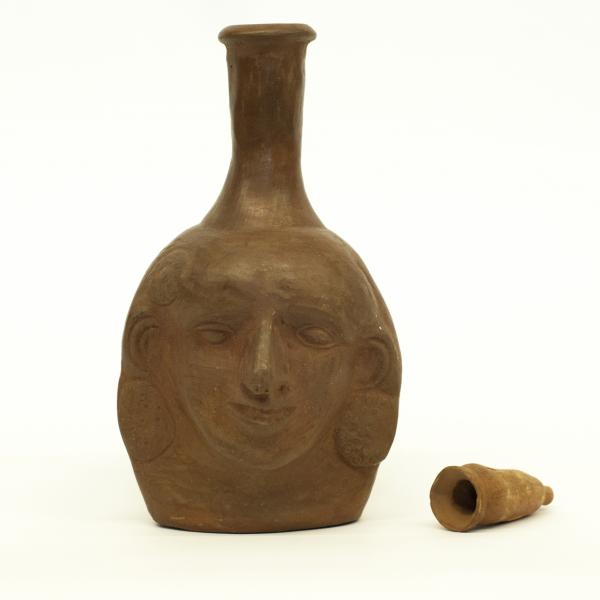 Front side of clay anthropomorphic jug showing the face with stopper removed. 