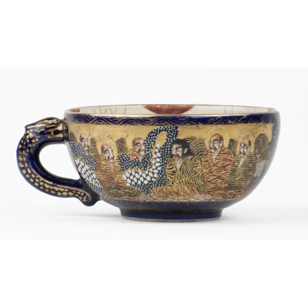 Tasse à thé Satsuma avec anse pointant à gauche. Le dessin montre six hommes, dont cinq sont auréolés, et la suite du corps du dragon. 