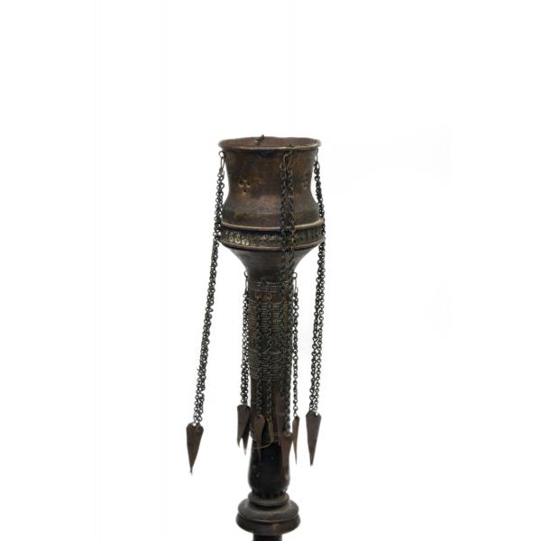 Top portion of a Persian water pipe, with pieces of metal chain hanging from the cup at the top. 