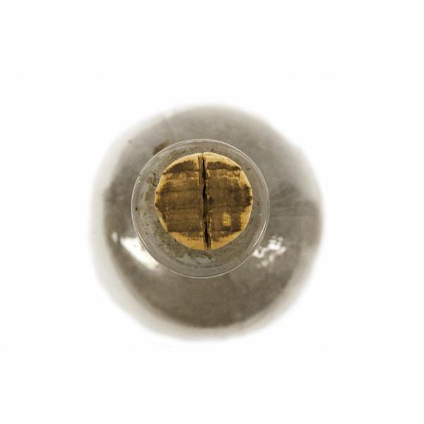 The top of a clear glass bottle filled with ash. There is a brown cork in the spout.