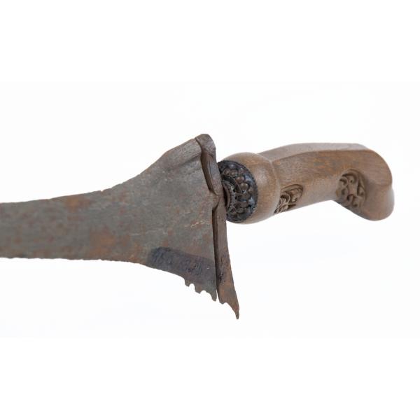 The base of a metal blade with a wooden handle. The blade is asymmetrical at the top and the handle has been carved. 