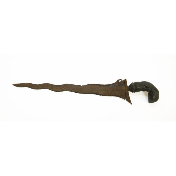 A rusted metal dagger pointing to the left. It has a curved brass handle etched with a design. The blade is wavy and asymmetrical. 