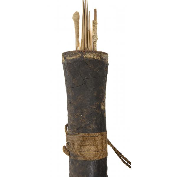 The top section of a woven reed quiver covered in cracked black rubber. There are light wooden darts wrapped in string sticking out of the top. Towards the bottom, brown string has been wrapped around the quiver.