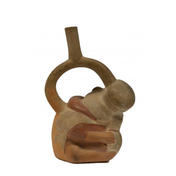 Front side of red and cream coloured stirrup-spout bottle in the shape of a crouched monkey. 