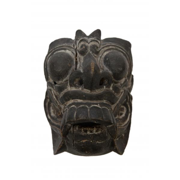 The front of a demon mask. It has large eyes, ears, a nose, and a mouth with large teeth. 