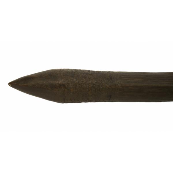 The point on a dark wooden club with raised veins in the grain. The end narrows into a pointed tip.