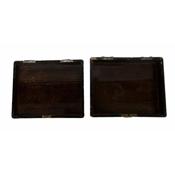 The inside of a black box, with the top and bottom halves next to each other showing the broken hinge. The paint is flecked with gold. 