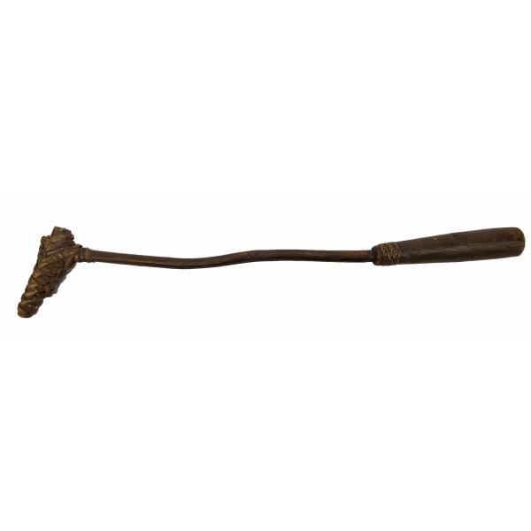 A dark wooden stick shaped like an "L" with a thin, plain shaft and a thicker handle with a line design carved into the base. There is a club on the end made with wood and wrapped in strips of wood. The base is pointing down. 