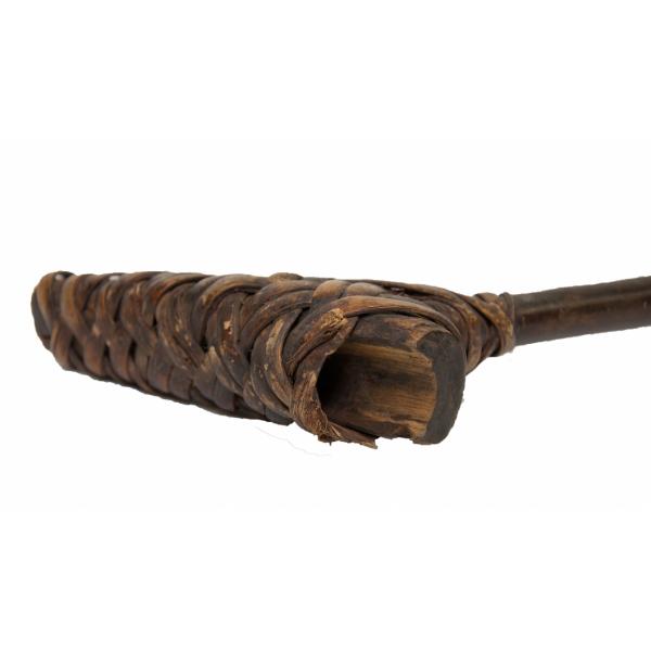 The base of a stick made from dark brown wood. Strips of wood are strapped around a short, hollow piece of wood to attach it to the shaft. 