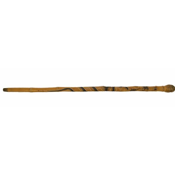 A light brown bamboo walking stick with a piece of metal on the end. The handle is bulbous and has circles carved into it. The shaft is decorated with images of monkeys and a snake that wraps around the cane.