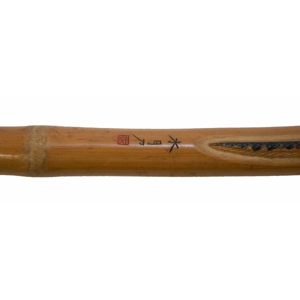 Japanese characters have been carved into the shaft of a cane and then painted red and black.