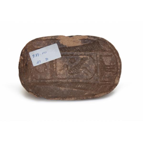 The bottom of a brown ceramic, human-headed scarab showing an incised cartouche. 