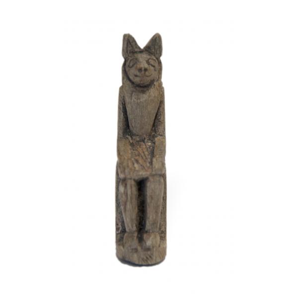 Le devant d’une statuette d’Anubis assis. Il a de grandes oreilles, des yeux, un nez et une bouche souriante. 