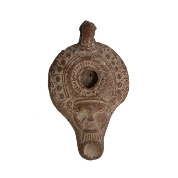 Top view of the terracotta oil lamp with raised decoration. Hathor is possibly depicted on the spout.   