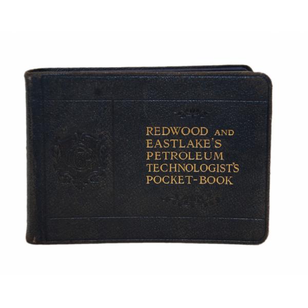 The blue front cover of "Redwood and Eastlake's Petroleum Technologist's Pocket-book", which is written in gold. There is a crest to the left of the writing and floral details above and below it. 