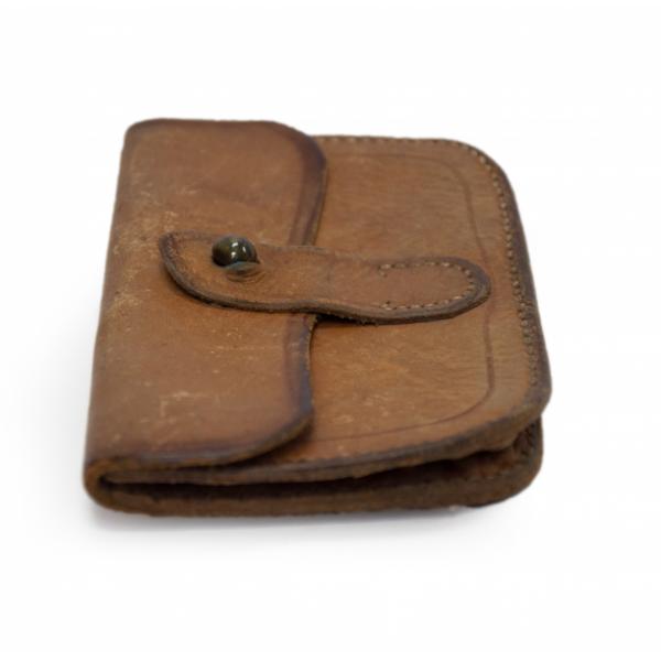 The side of a small, brown, leather pouch. It has a folded top flap and button clasp that is closed.  