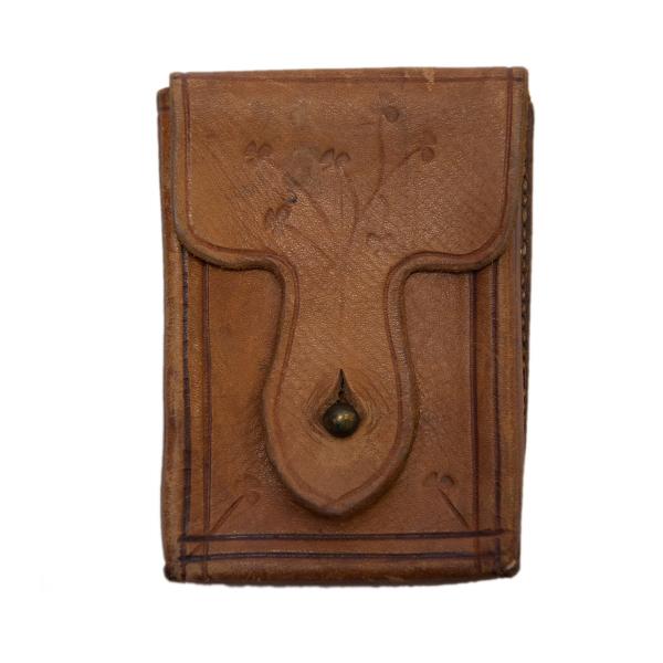 The front of a rectangular leather pouch with a line border along the edge and flower buds on the front flap closure. There is a button keeping the case closed. 