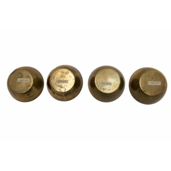 The bottom of four brass finger bowls with flared sides and flat bottoms.  