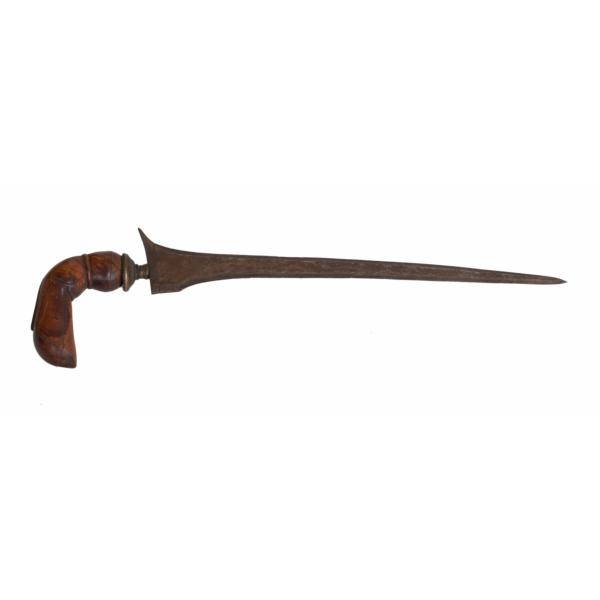 A metal dagger with an asymmetrical blade. The handle is made of wood and is curved and carved. There is a piece of metal where the handle meets the blade. 