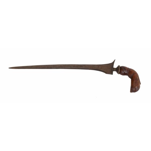 A metal dagger, pointing left, with an asymmetrical blade. The handle is made of wood and is curved and carved. There is a piece of metal where the handle meets the blade