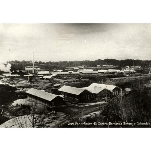 Vista shot of the main camp at an oil field in Colombia. There are three long buildings in the foreground and a group of buildings in the background. 