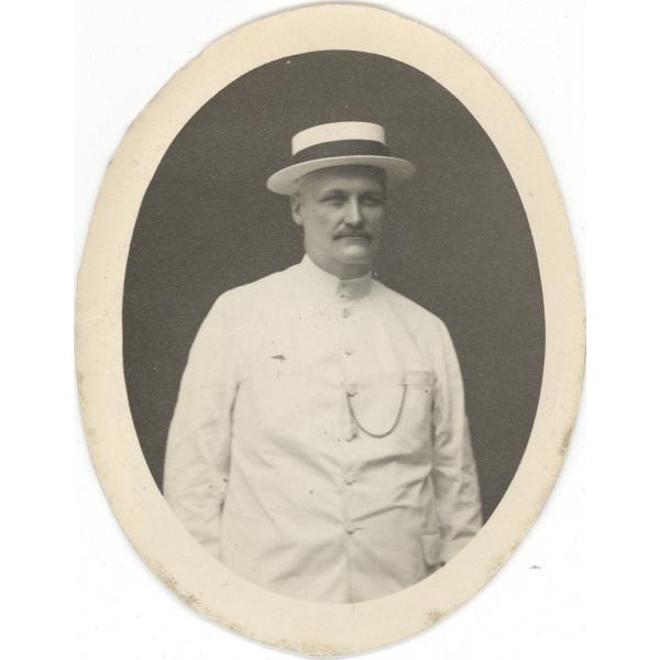 Oval portrait shot of William McRae in a white suit and panama hat. 