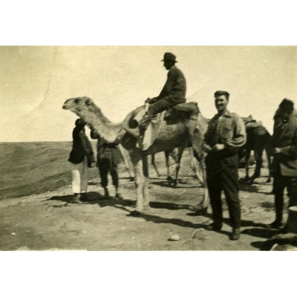 An International Driller on a camel, with another posing on the ground. There are a number of local men with them.