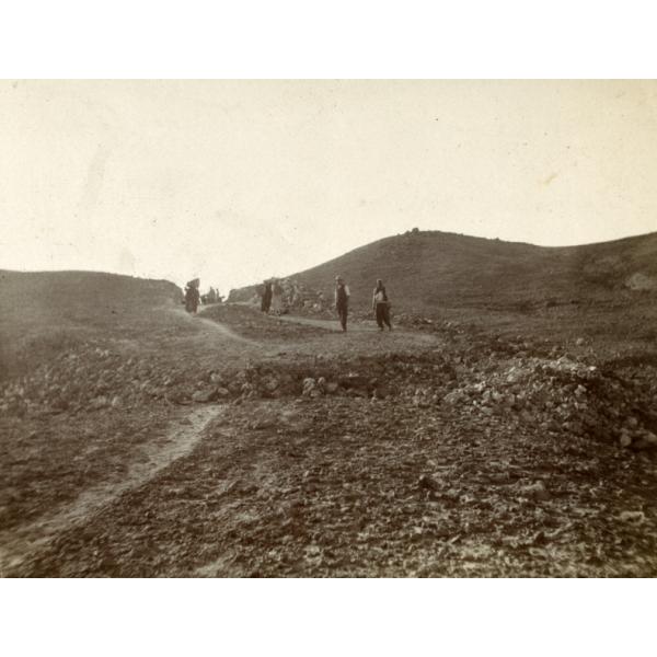 A photo of a group of men balancing baskets on their heads, walking along a stone road. Campbell stands toward the front with another man.