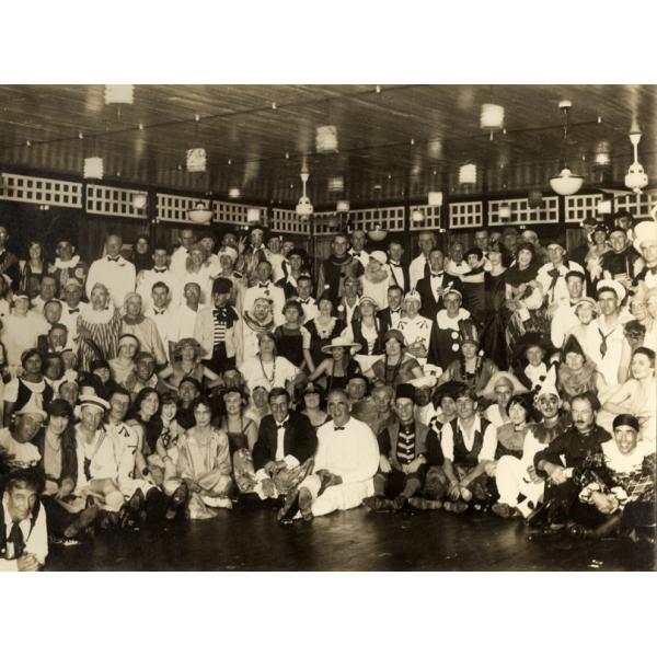 A photo of a large group of people dressed up in costumes. They are in a large room with wooden floors and paper lanterns hanging from the ceiling.