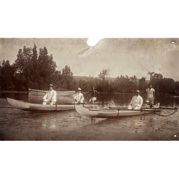 Trois foreurs internationaux, deux dans un canot et un dans un autre. Un homme de la région se trouve également dans chaque canot. Un troisième canot se trouve en arrière-plan.  