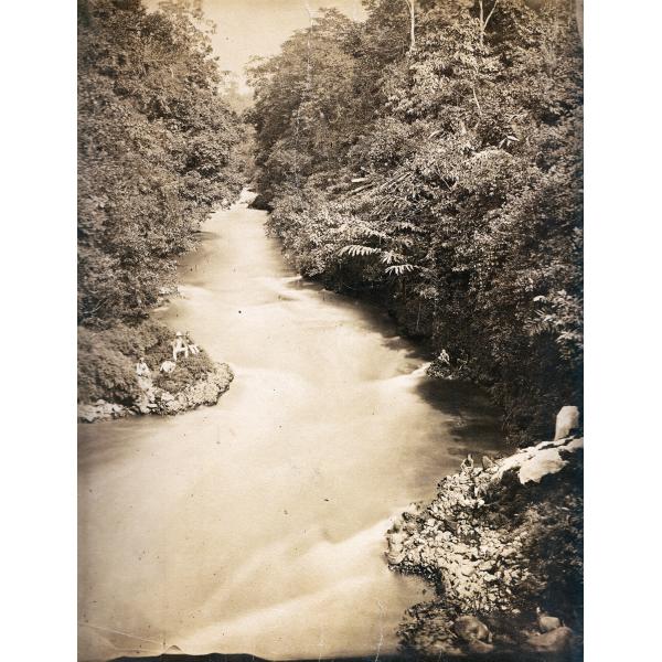 A river winding between trees, with a group of people sitting on a small point that juts out into the water.  