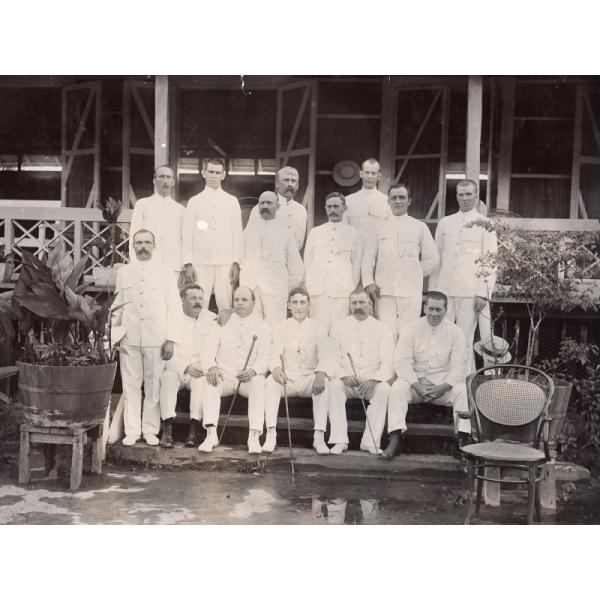 Group photograph of foreign drillers in Borneo all wearing white suits. They are posed in front of a building on a set of steps. 