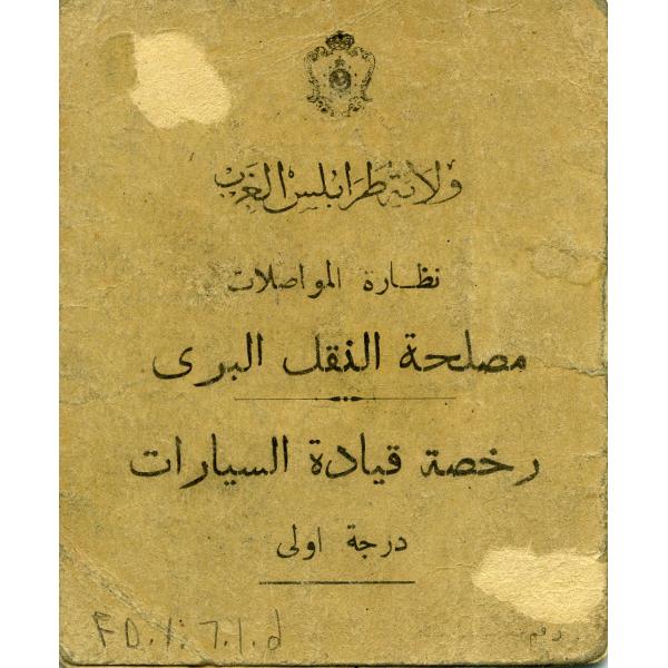 The back of a driving licence. It is light brown. There is a crest at the top followed by five rows of black Arabic text. 