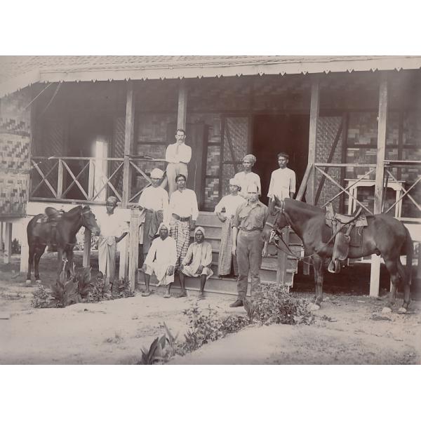 Group of oil drillers in Burma, outside their quarters. Joe Scarborough is standing at the top and Bill Hutchinson is standing with a horse.