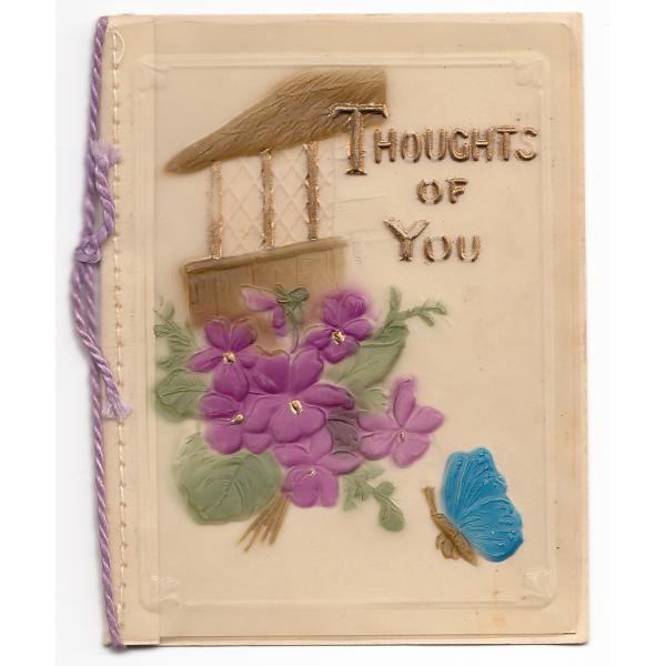 The front of a Christmas card with purple flowers on it. There is a brown building in the background and a blue butterfly in the foreground. There is a piece of purple string along the fold. The card says, "Thoughts of You".