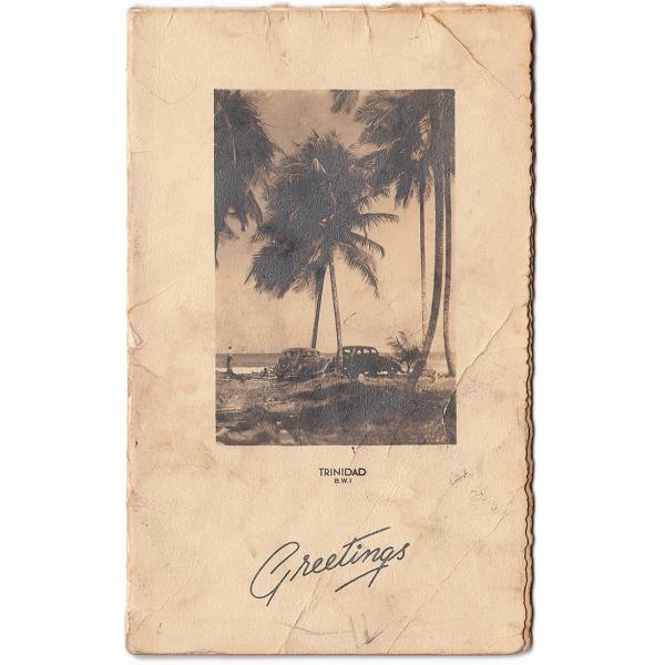 The front of a Christmas card that shows an image of palm trees, two cars, and a person in front of the ocean. It says: "Trinidad B.W.I. Greetings".  