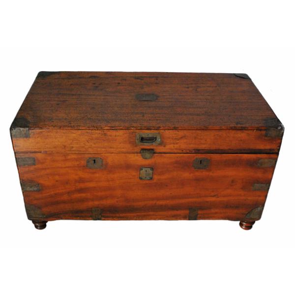 A smooth wooden chest with a reddish hue. There are pieces of brass on the corners. The lock is also made of brass.