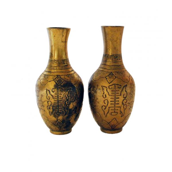 A pair of brass vases with a symmetrical line pattern on the body and a line design on the necks.