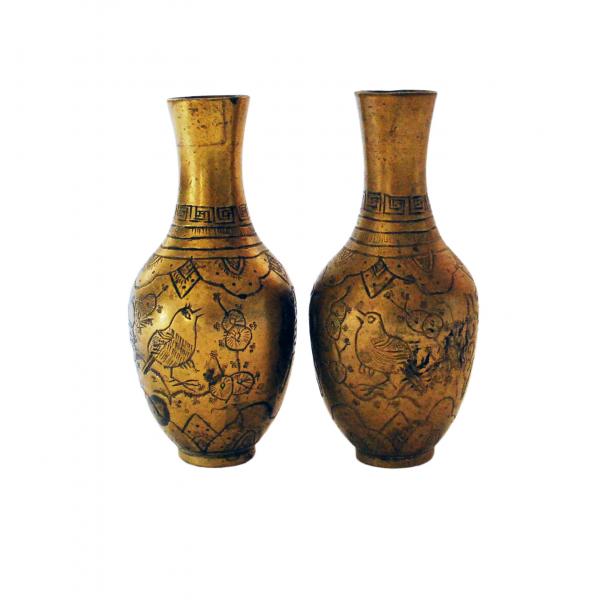 A pair of brass vases. There is a bird sitting in a tree on the bodies of the vases. There is a line design on the necks of the vases.