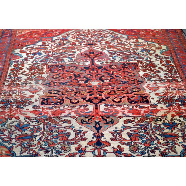 A red rug with a blue, white, orange, green, and yellow motif.  