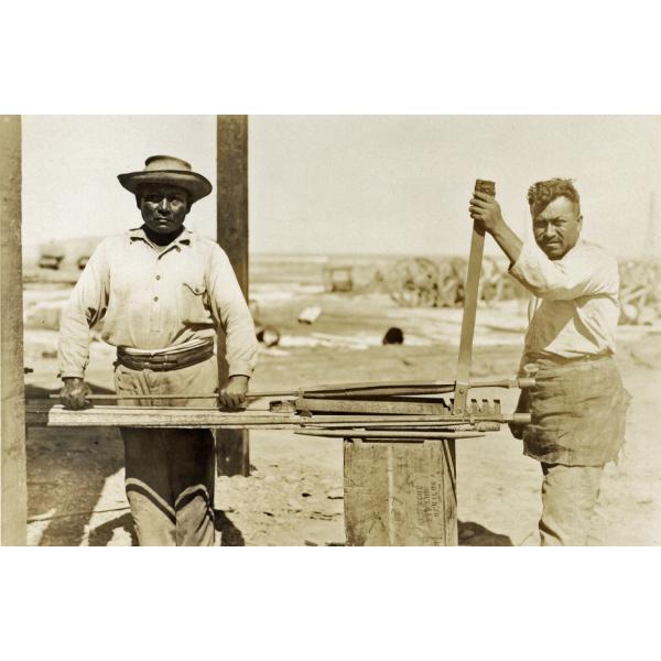 Two Peruvian men placing guides on sucker rods. 